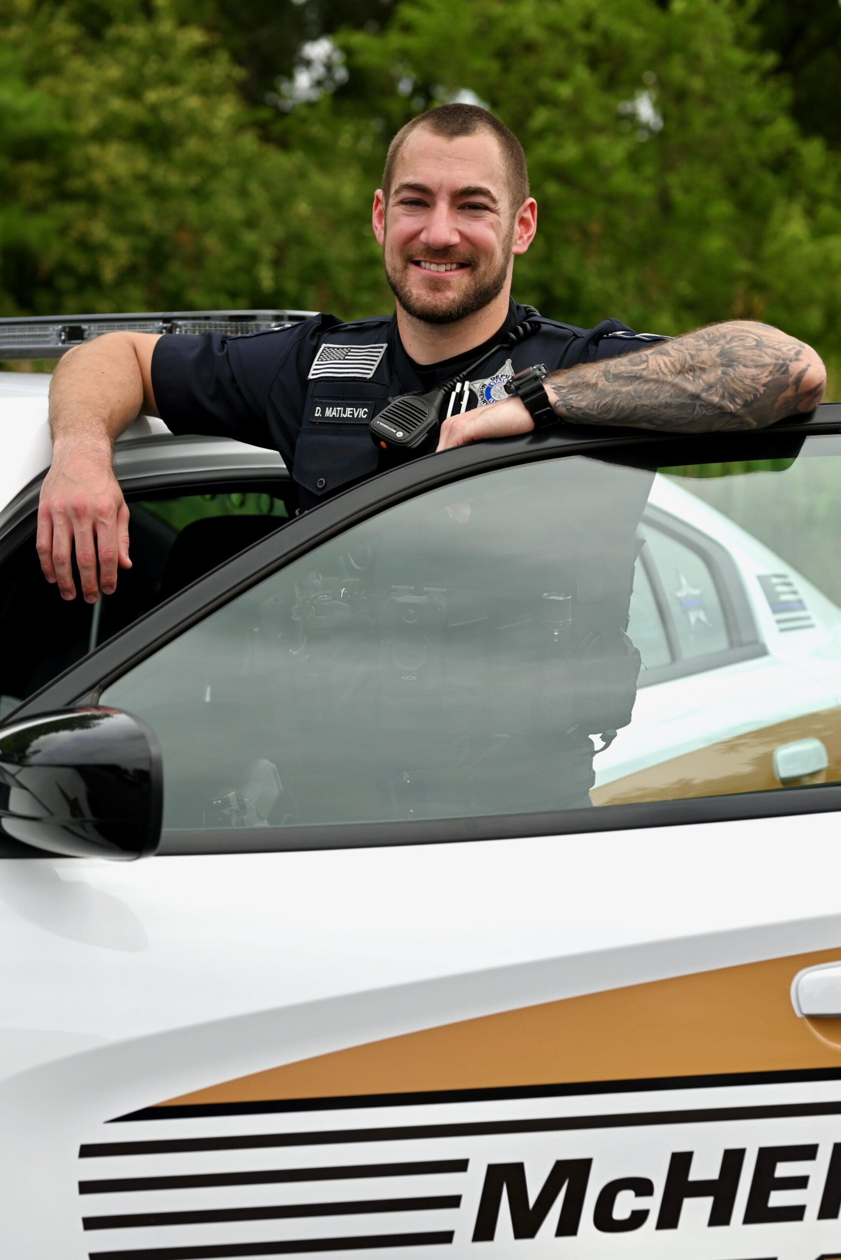 Deputy standing with arms on door of squad car